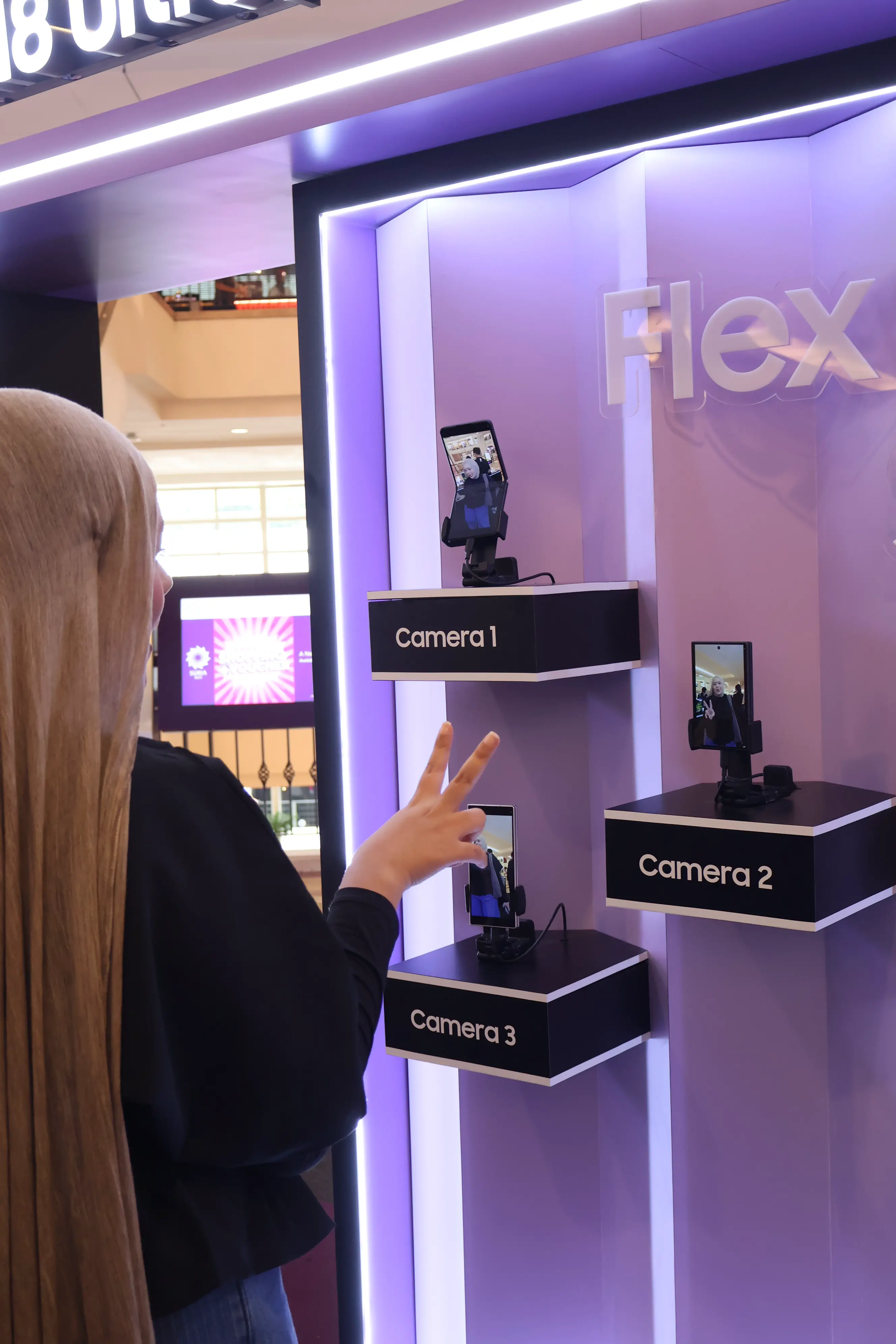 Guest flashing a peace sign at the three Galaxy foldable camera stations
