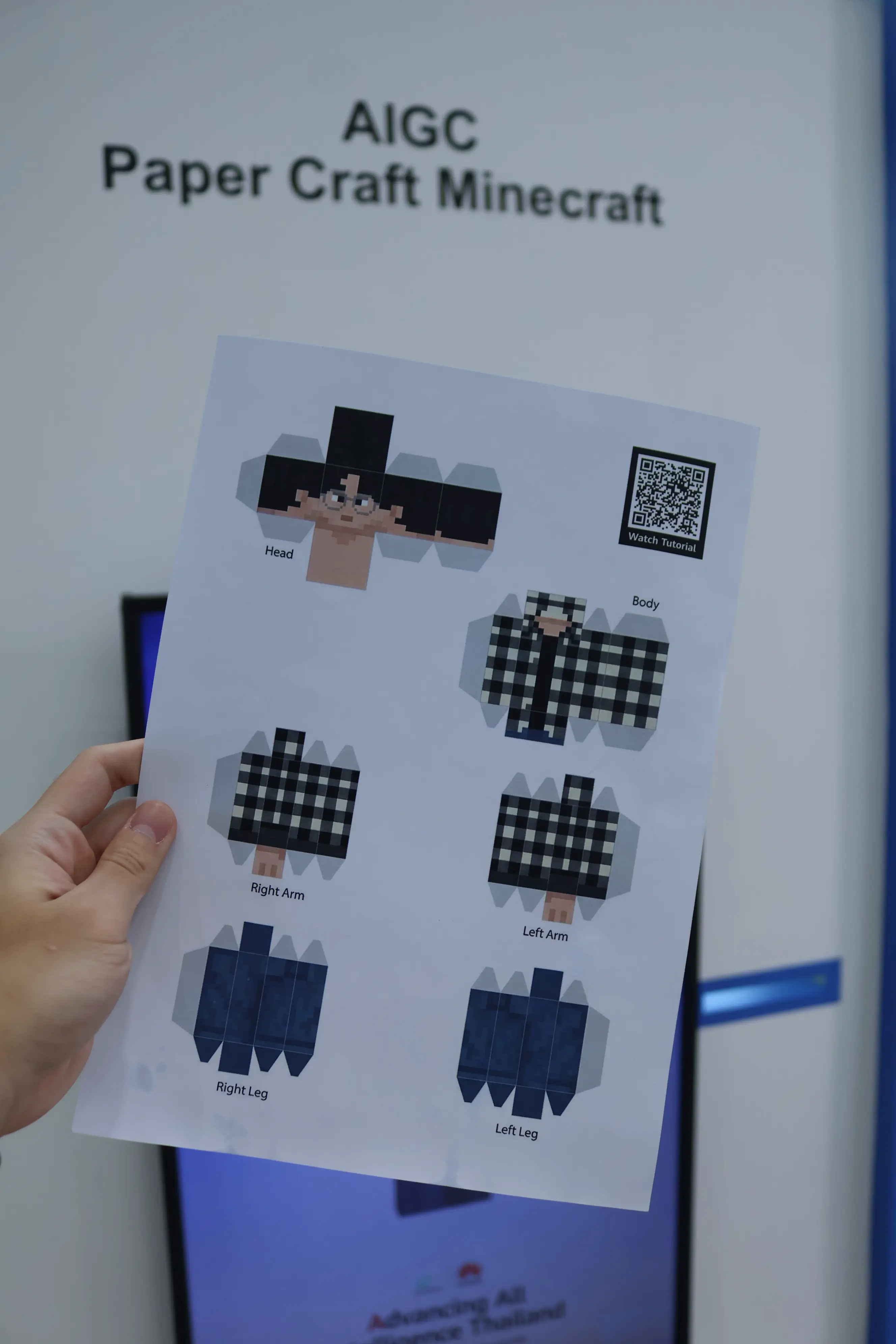 Hand holding a printed papercraft Minecraft character sheet with QR tutorial code