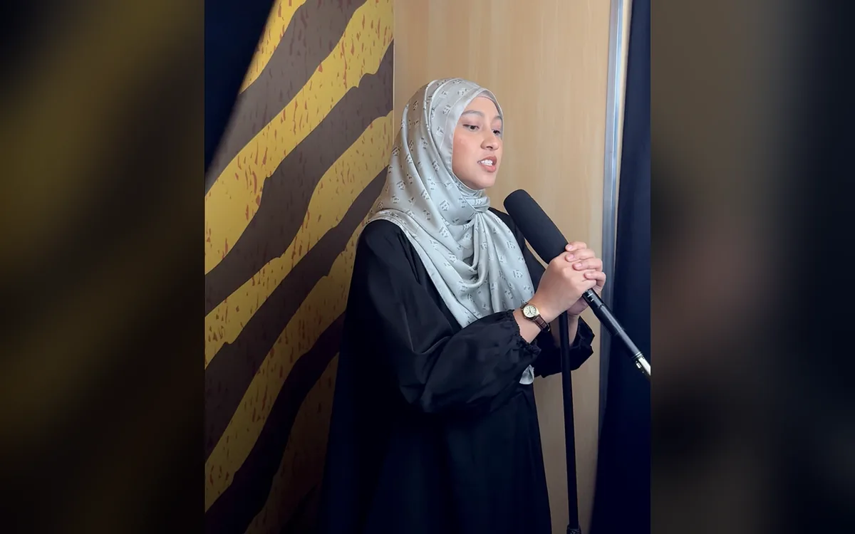 Guest singing into the microphone in the Maybank Tiger Summit karaoke booth against a tiger-stripe backdrop