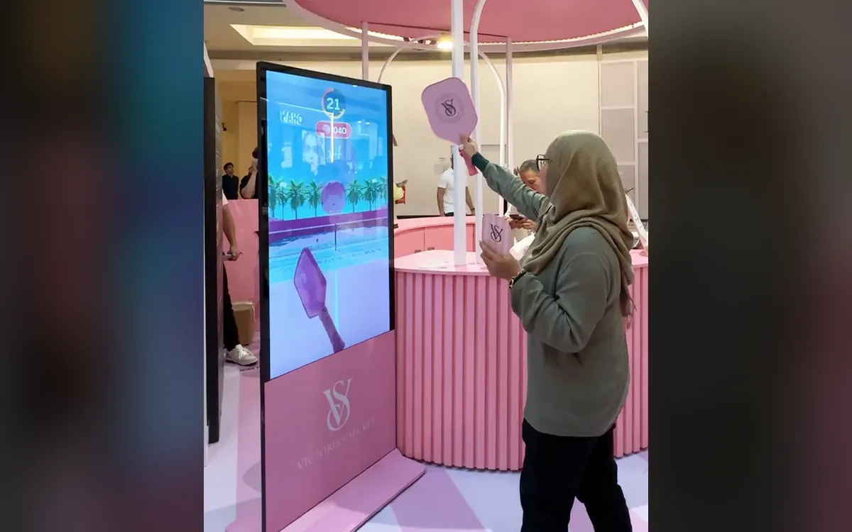 Shopper swinging the sensor paddle to play the Victoria's Secret VSX pickleball game at Suria KLCC