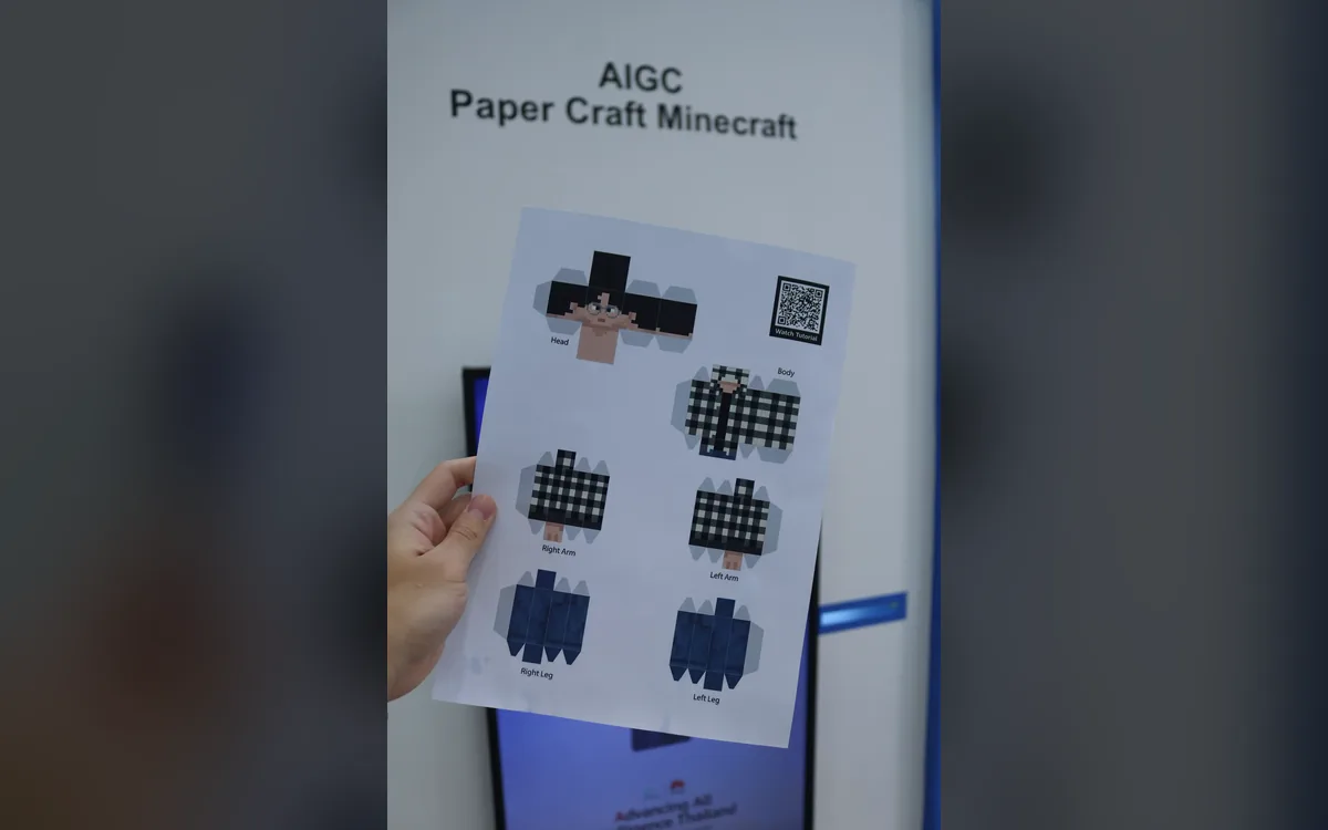 Hand holding a printed papercraft character sheet from the Huawei ICT AI booth in Bangkok