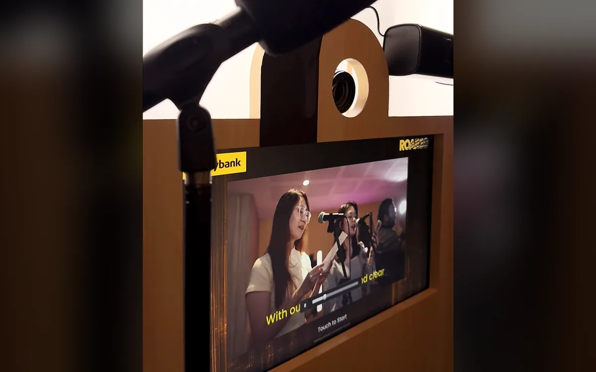 Karaoke booth screen showing guests singing at microphones with on-screen lyrics at the Maybank Tiger Summit in Malaysia