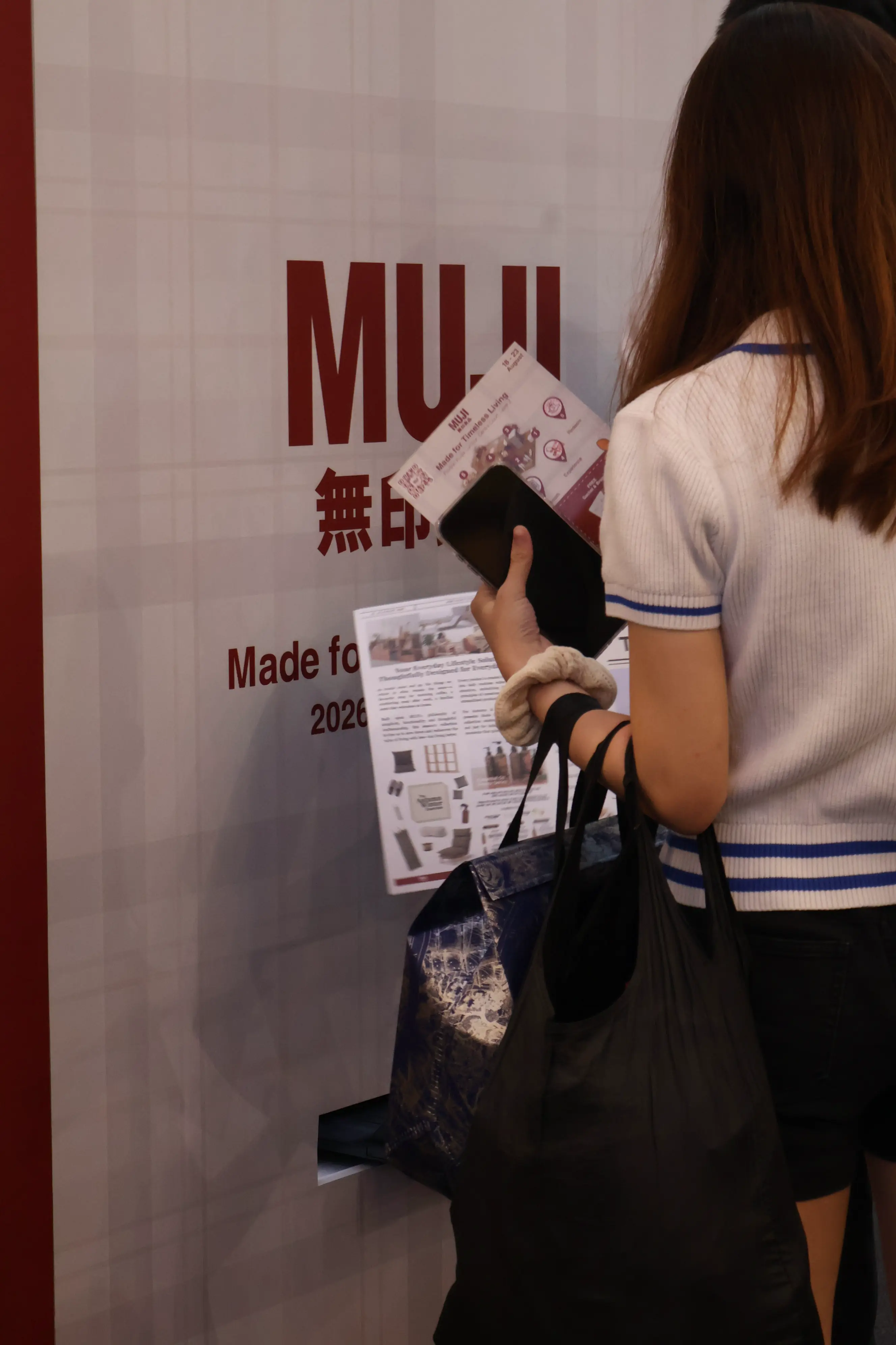 Shopper collecting her printed MUJI newsletter photo from the booth print slot