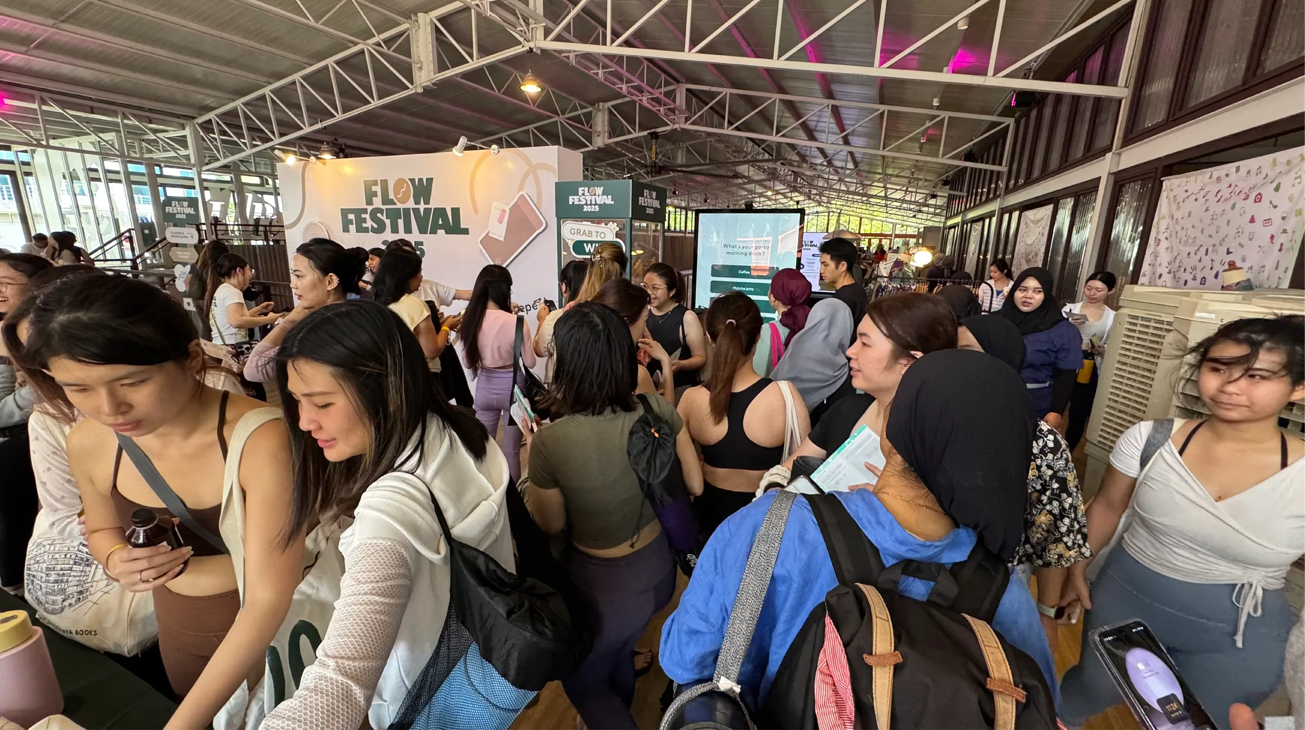 A crowd of attendees gathers near the Flow Festival booth and quiz screen.