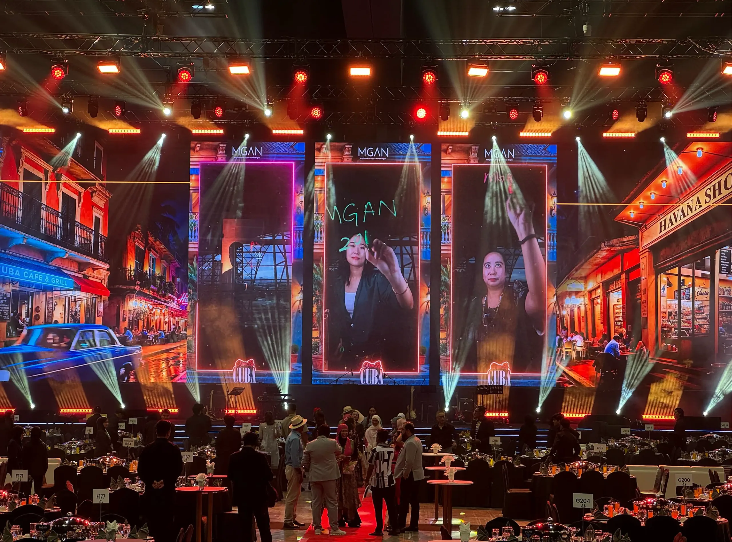 Attendee portraits appear on giant LED screens against a Havana-themed gala backdrop.