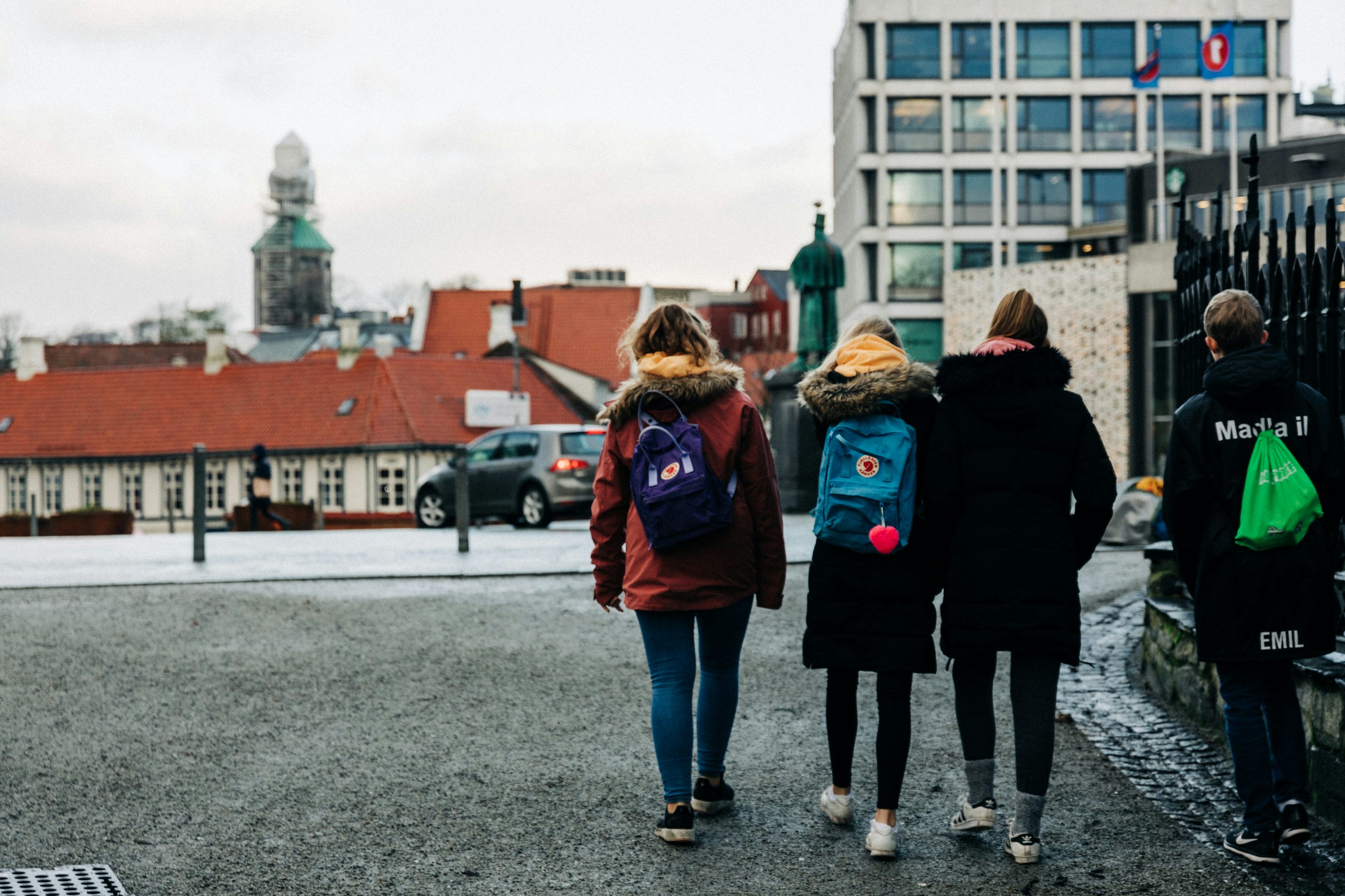 four persons walking on concrete road during daytime