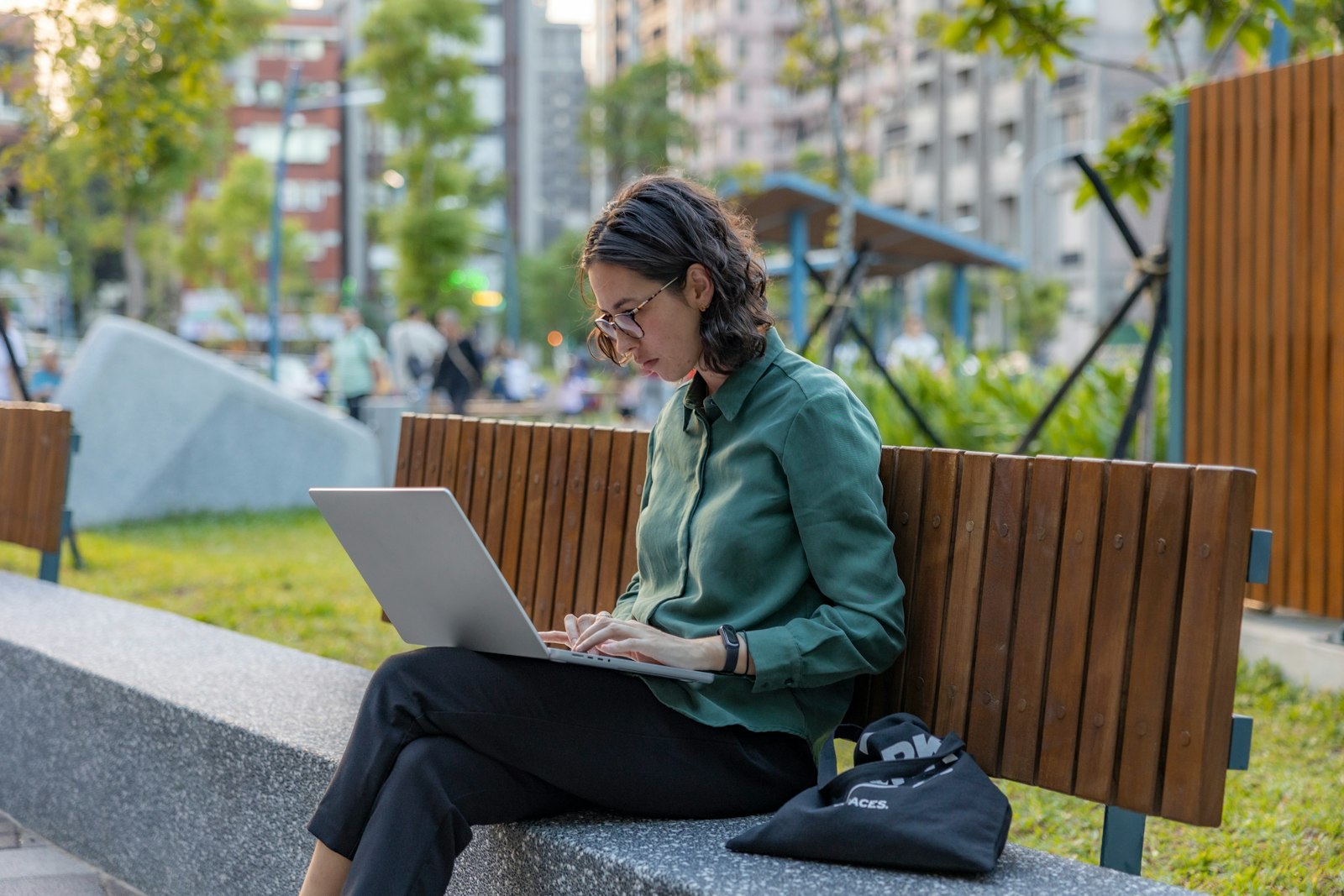 Woman working remotely on a laptop at a park bench