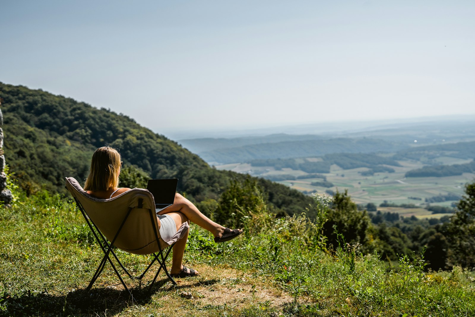 Woman working on a laptop at a scenic mountain overlook