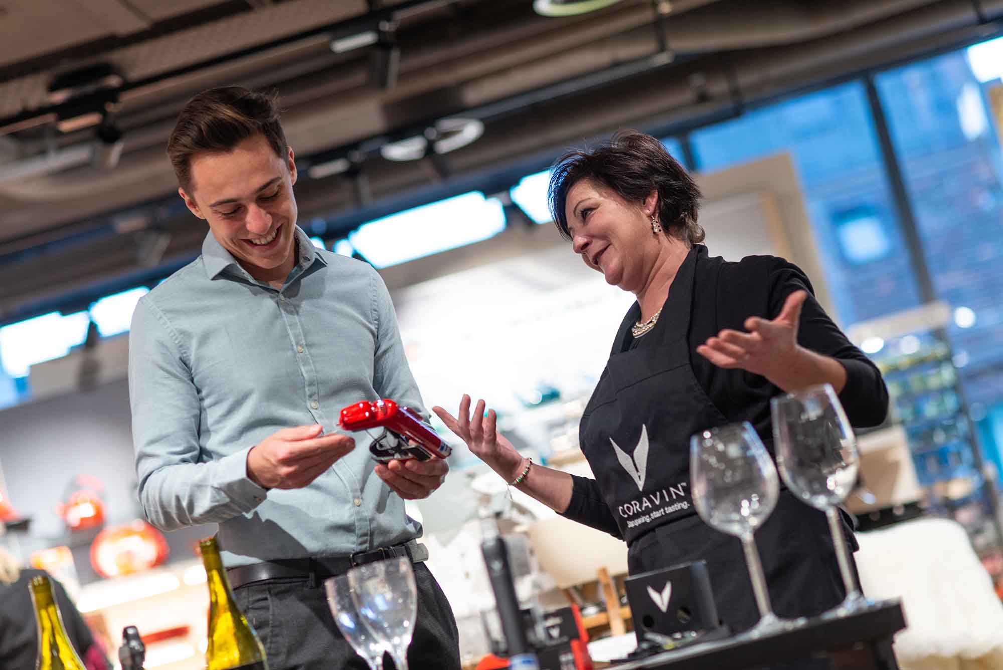 Frau in schwarzer Uniform zeigt einem Mann im Hemd ein Muster des Produkts ihrer Firma