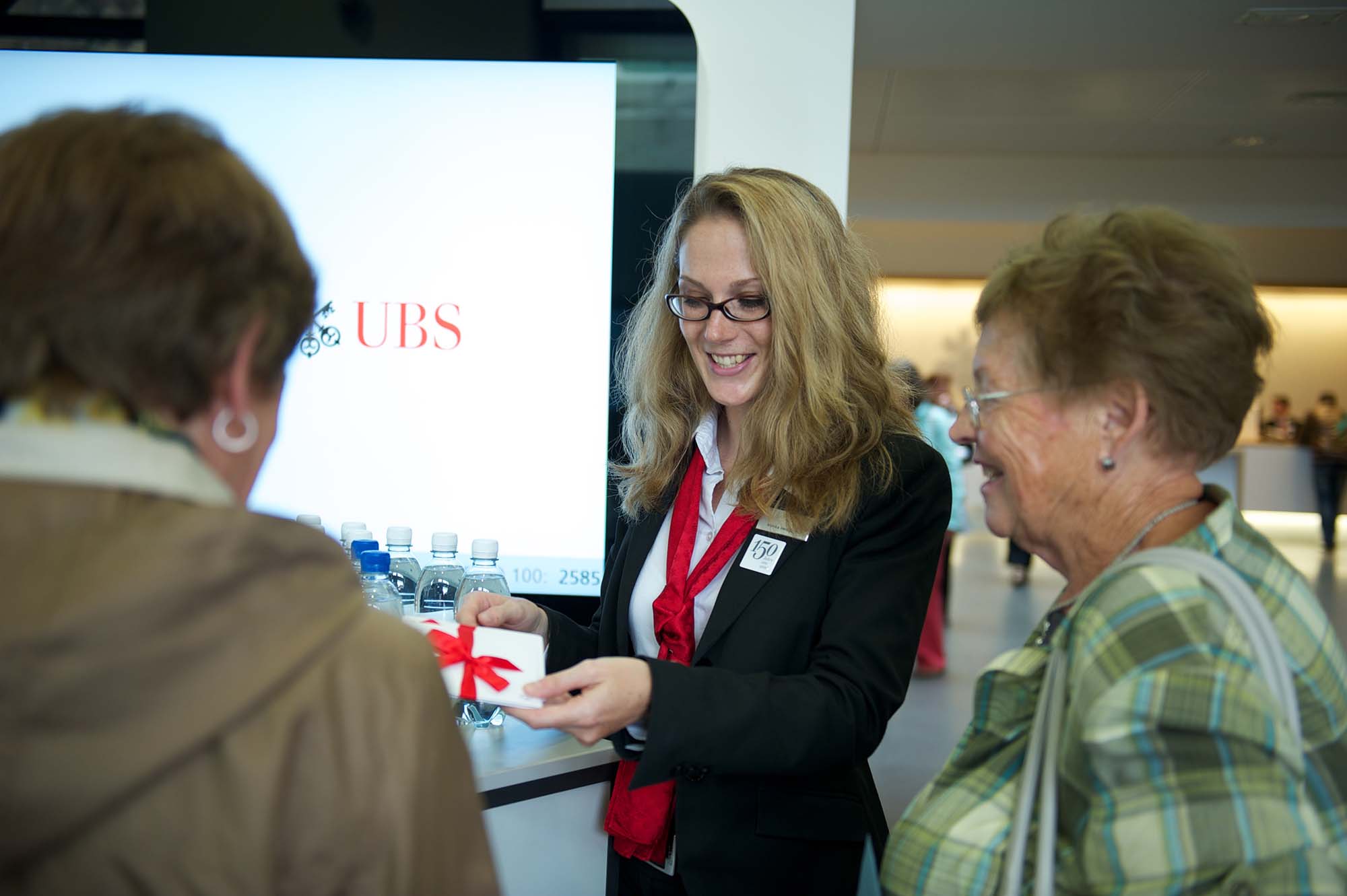 Eine beschäftigte Mitarbeiterin zeigt UBS-Waren den Kunden