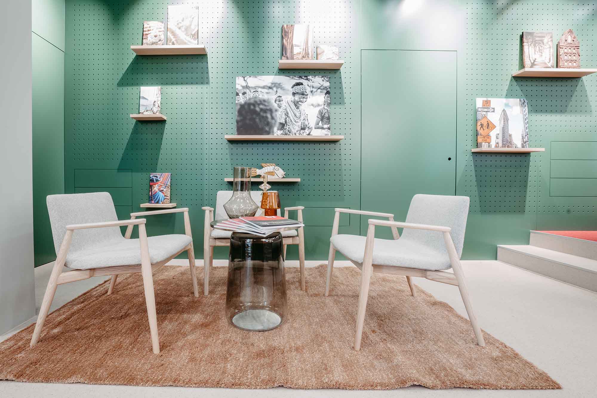 Couchtisch mit zwei weißen Stühlen vor einer grünen Wand.