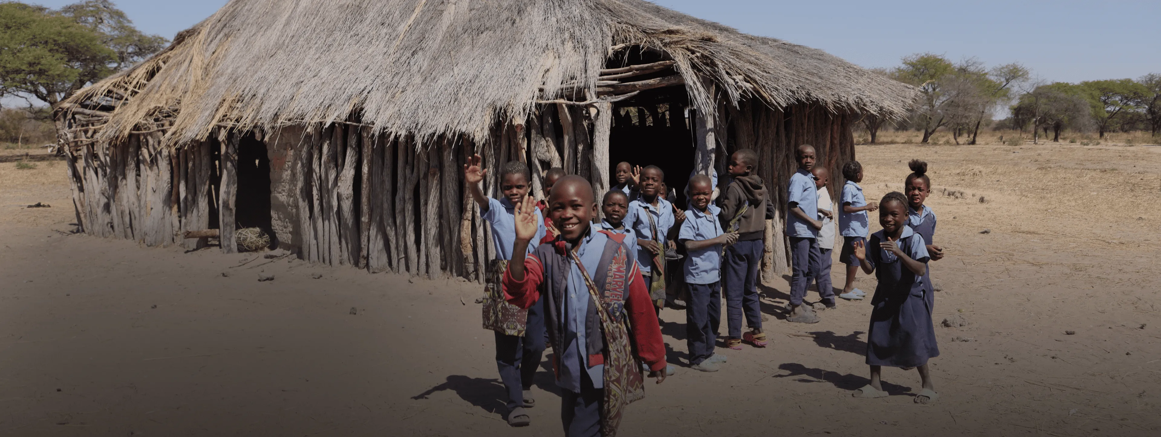A group of people standing in front of a hut.