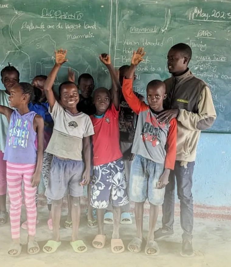 A group of children standing in front of a chalkboard.