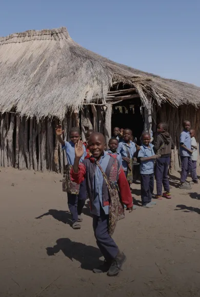 A group of children in front of a hut.