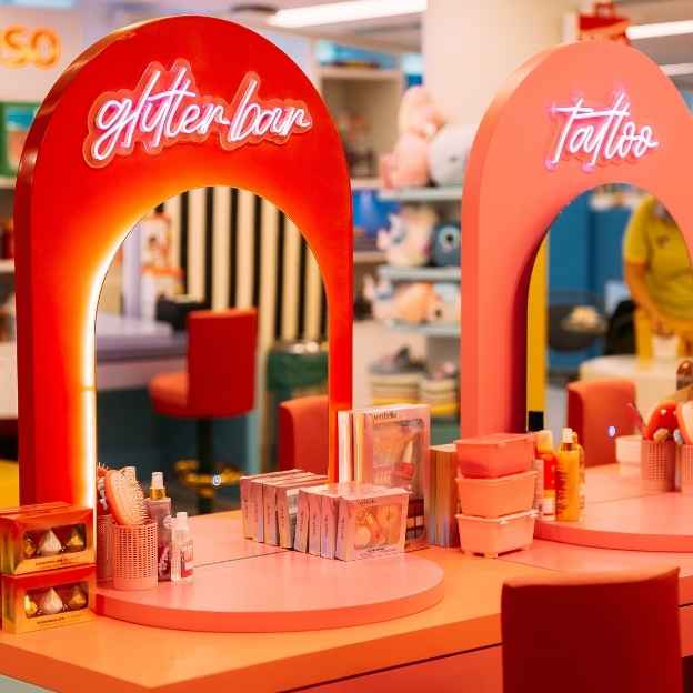 Four striped popcorn containers filled with different flavors: yellow butter popcorn, caramel popcorn, red candy-coated popcorn, and pink popcorn. The background features colorful patterns.