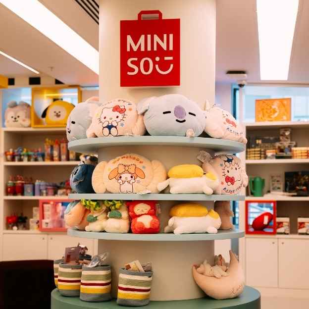 Three decorative cakes displayed on a blue background. The left cake features colorful meringue peaks and a red base, the center cake has white frosting with a red topping, and the right cake has swirled pink frosting with a drippy edge.