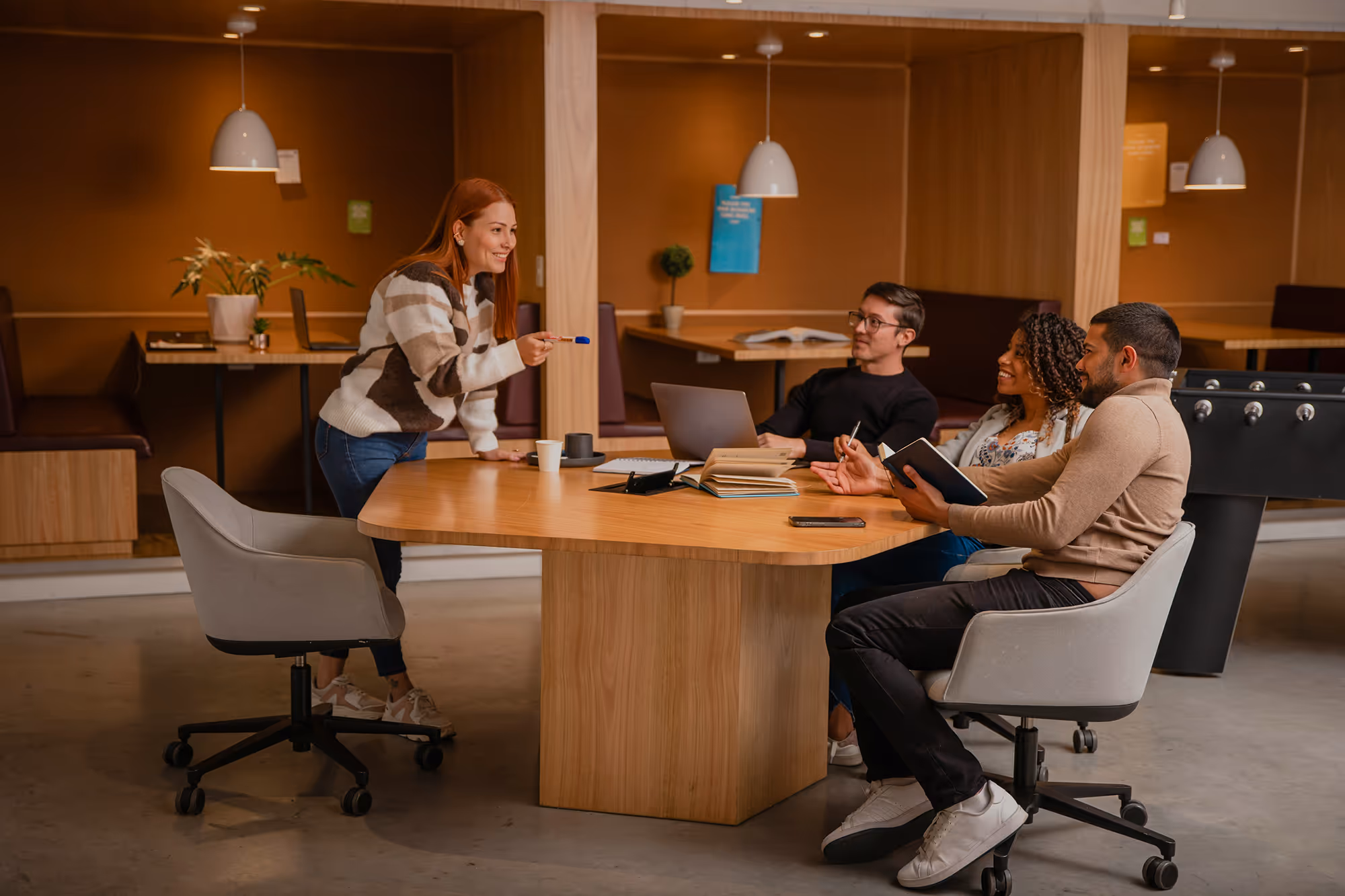 A group of people sitting around a desk in a modern looking office space.