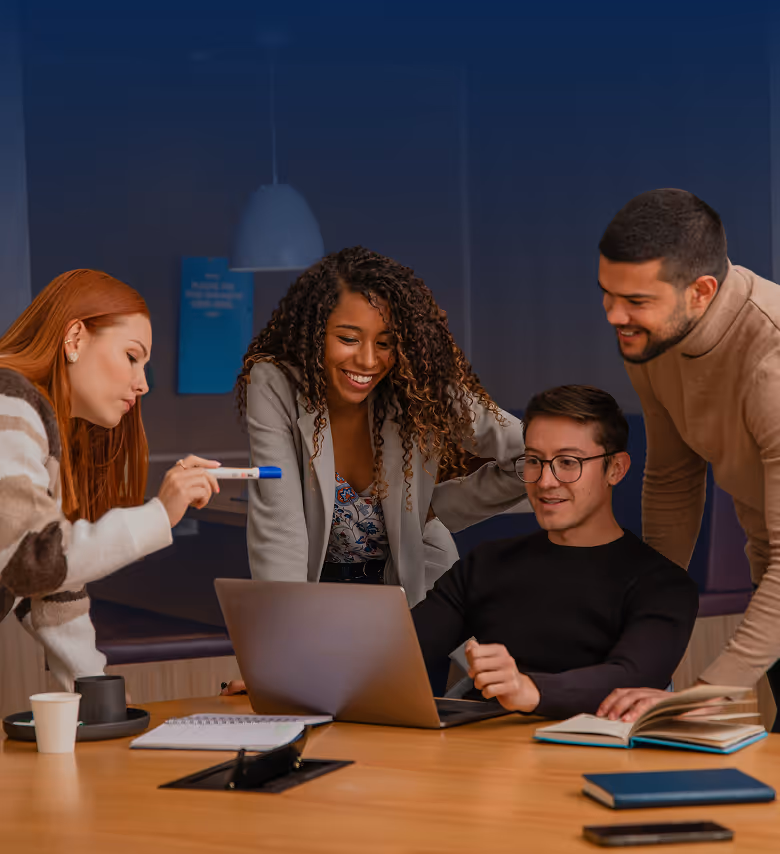 A group of people working around a desk smiling.