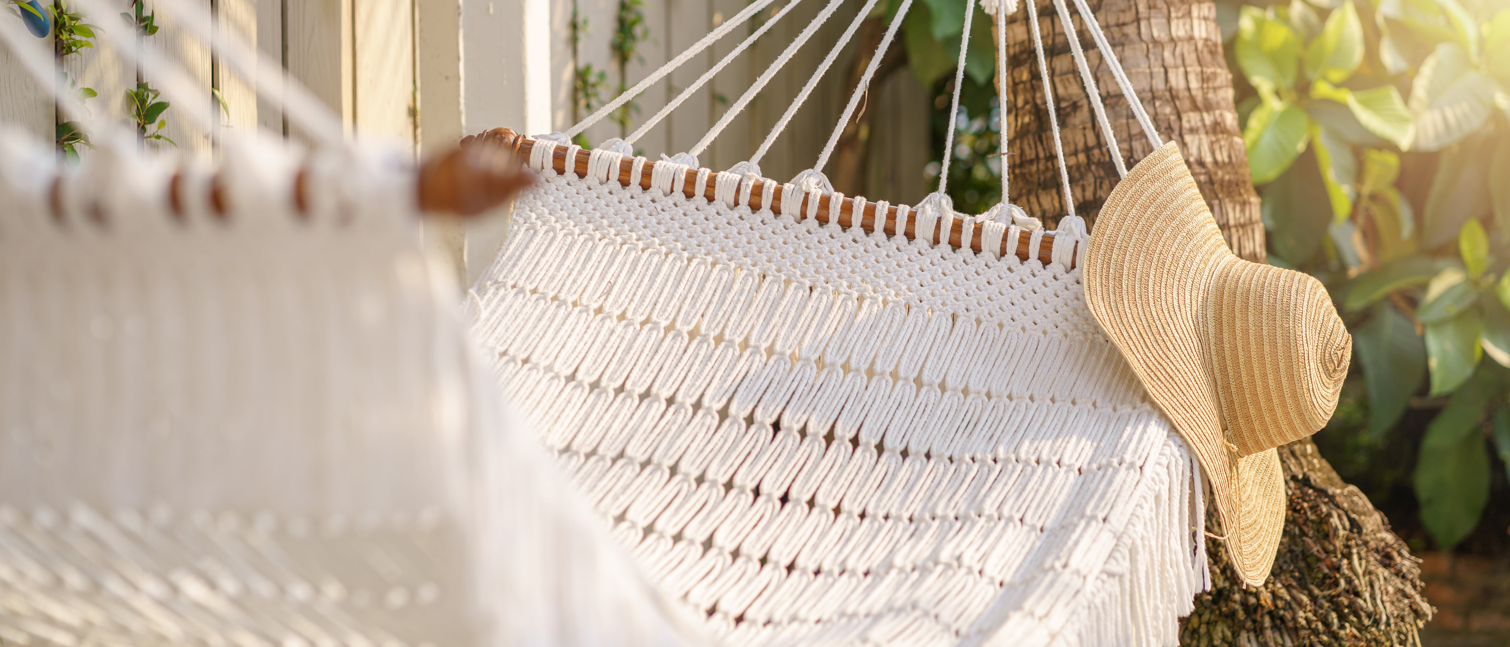 A white hammock with a straw hat on it.