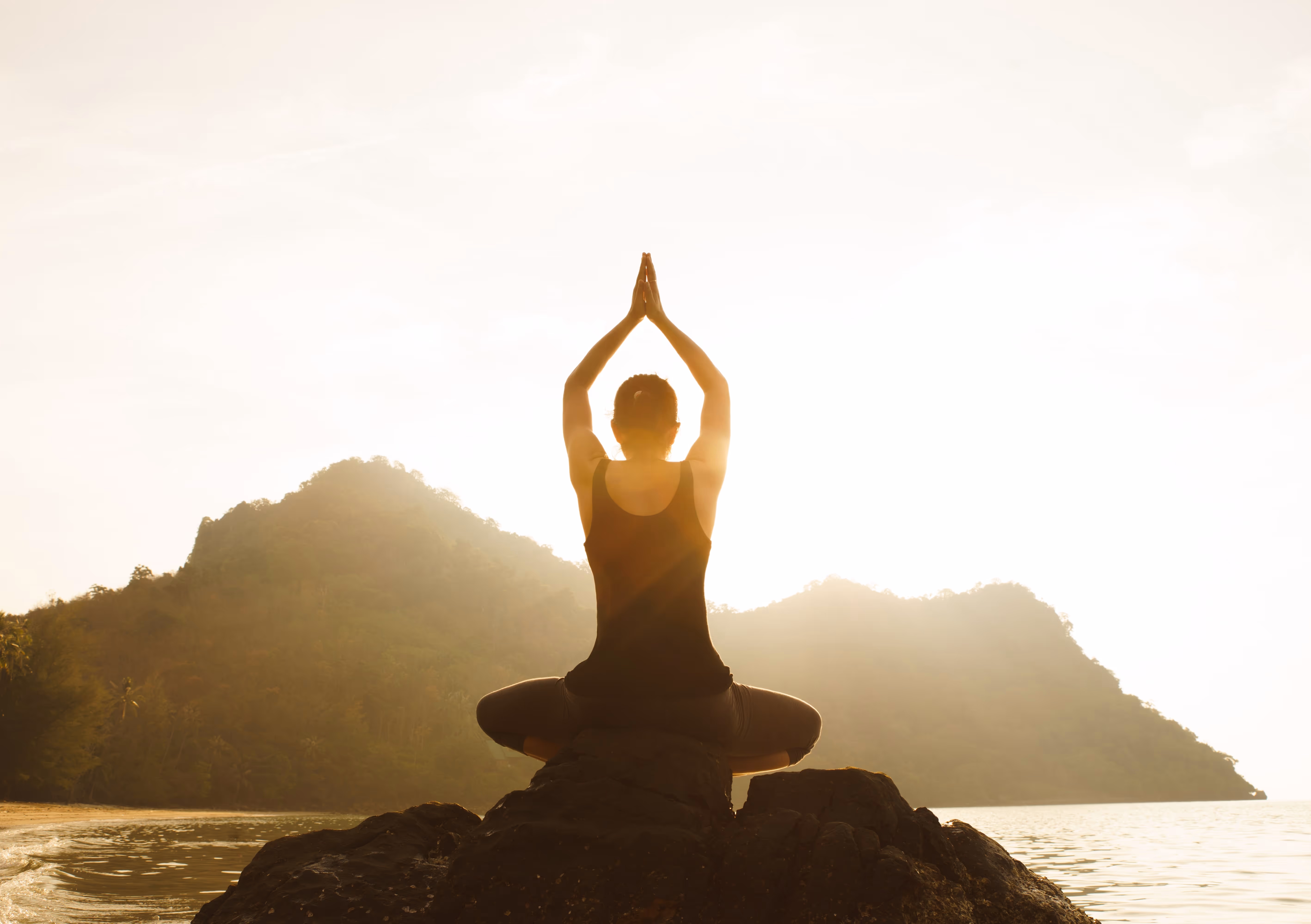 A person sitting on a rock doing yoga.