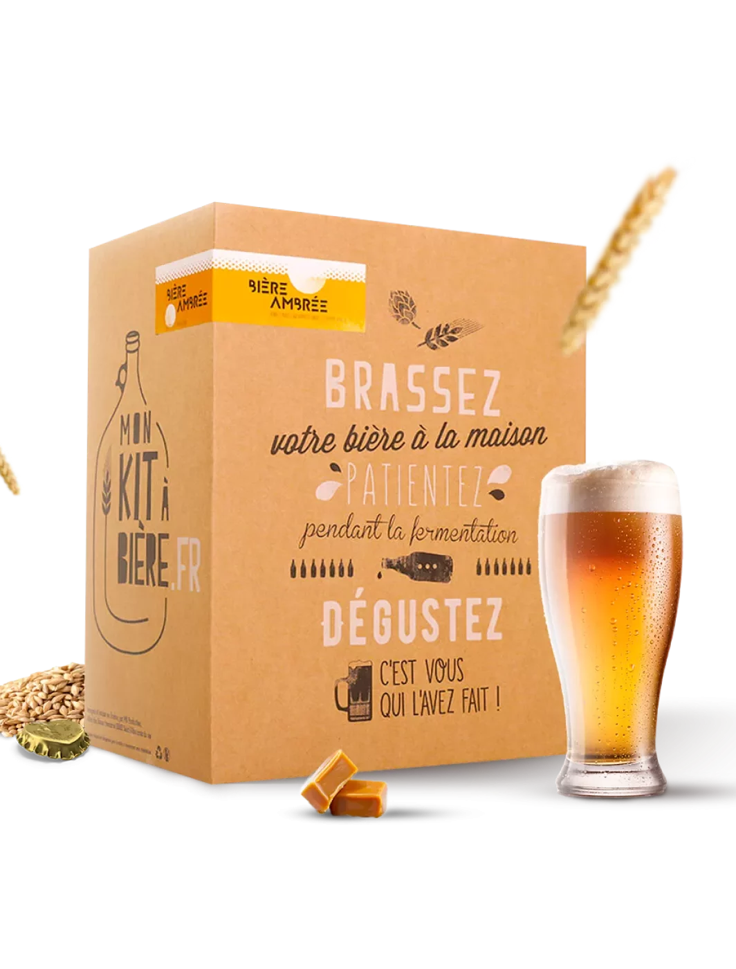 Kit de brassage de bière ambrée avec une boîte illustrée montrant les étapes de brassage, de fermentation et de dégustation, accompagné d'un verre de bière ambrée et de cônes de houblon.