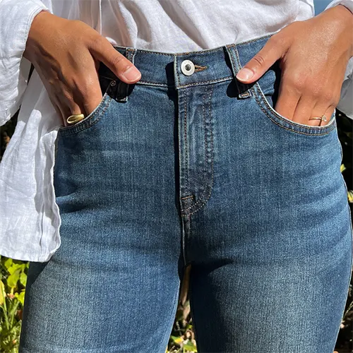A close up of a woman with ther hands in the jeans' pockets.