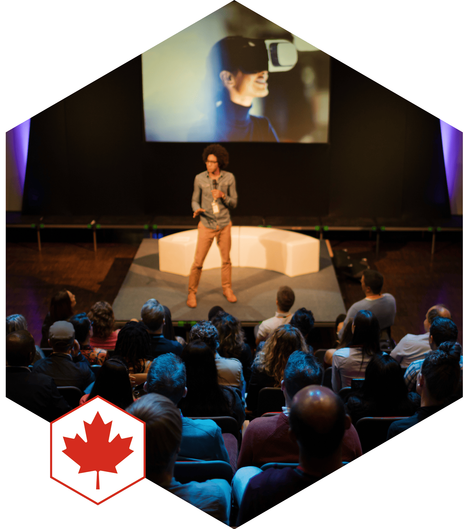 A speaker on a stage presents to an audience.
