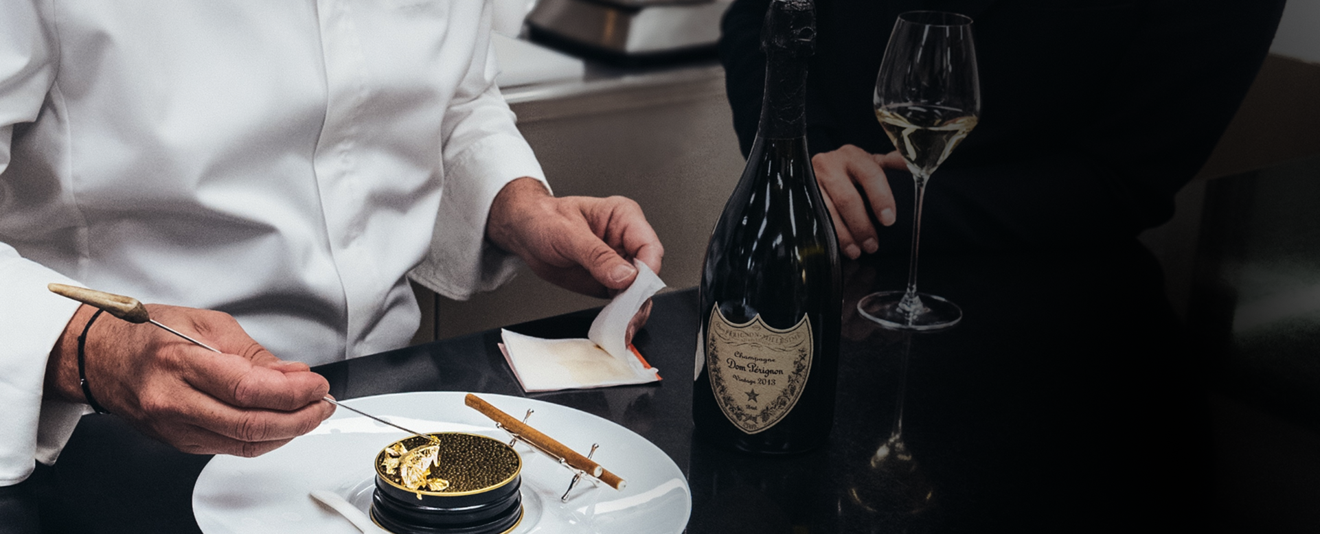Chef plating caviar alongside champagne
