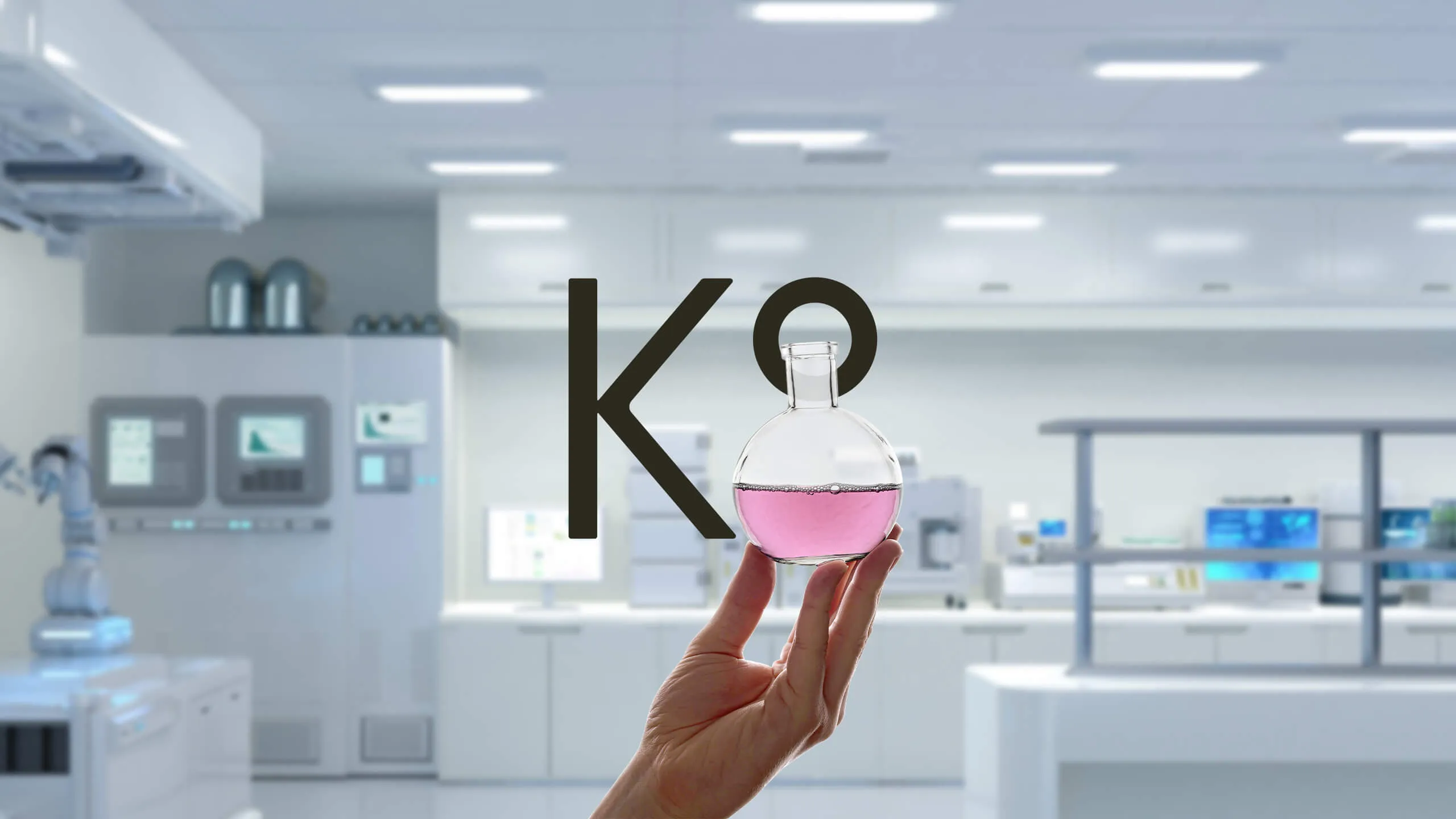 K8 logo in a lab while a hand holding a round flask displaying half of the 8