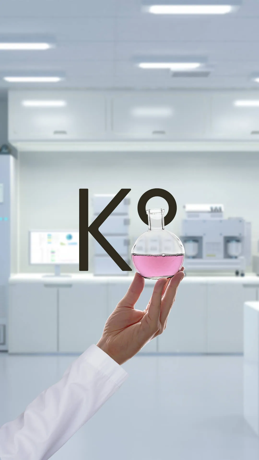 K8 logo in a lab while a hand holding a round flask displaying half of the 8