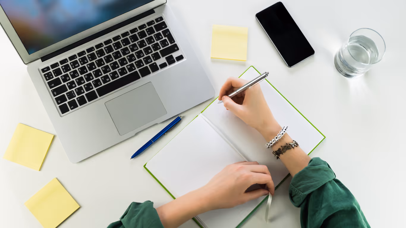 woman writing in front of a laptop
