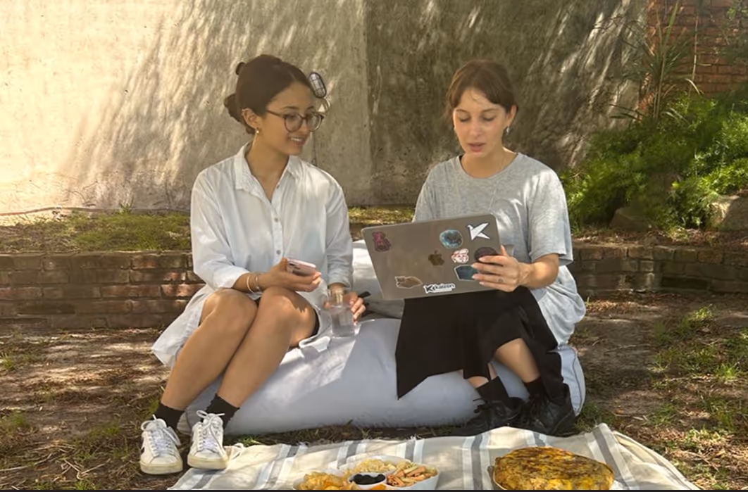 Two women at Kaizen Softworks exemplifying our flexible and collaborative culture by working together on a laptop outdoors. This reflects our commitment to teamwork and work-life balance.