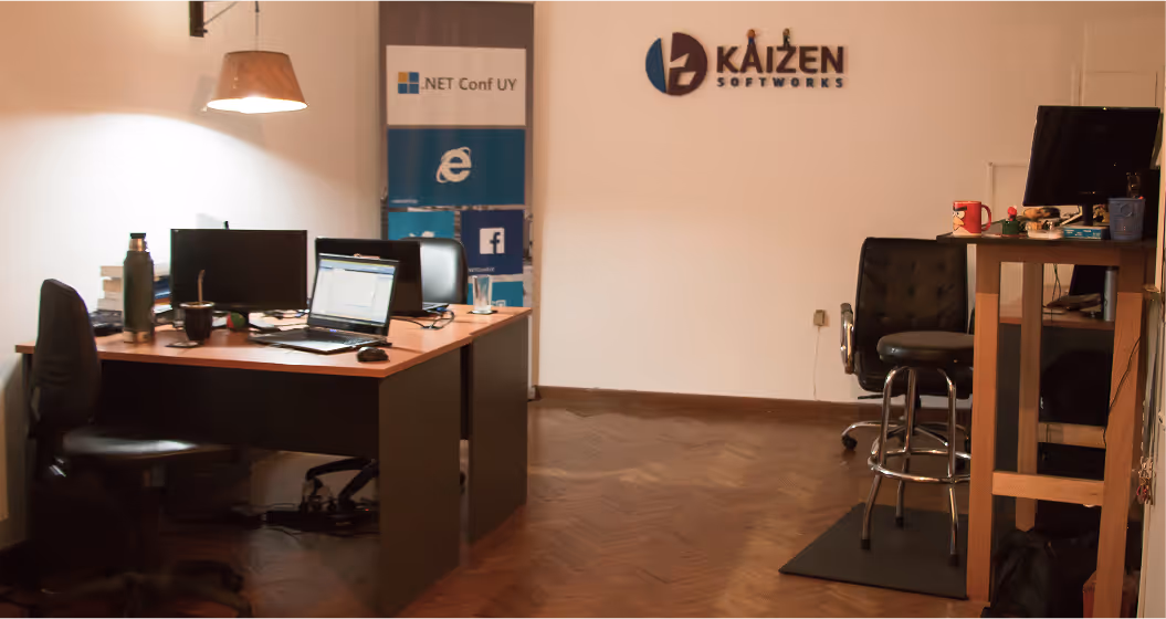 The first office of Kaizen Softworks, where our journey in custom software development began in a founder's backyard in Montevideo. The image shows our original logo and the desk where our first projects were built.