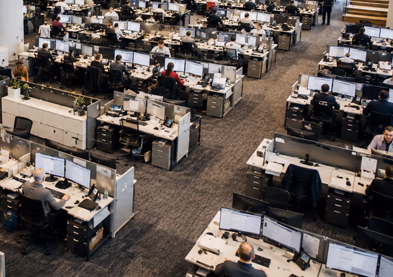 Large operations office showing back-office teams managing manual status updates and document reviews.