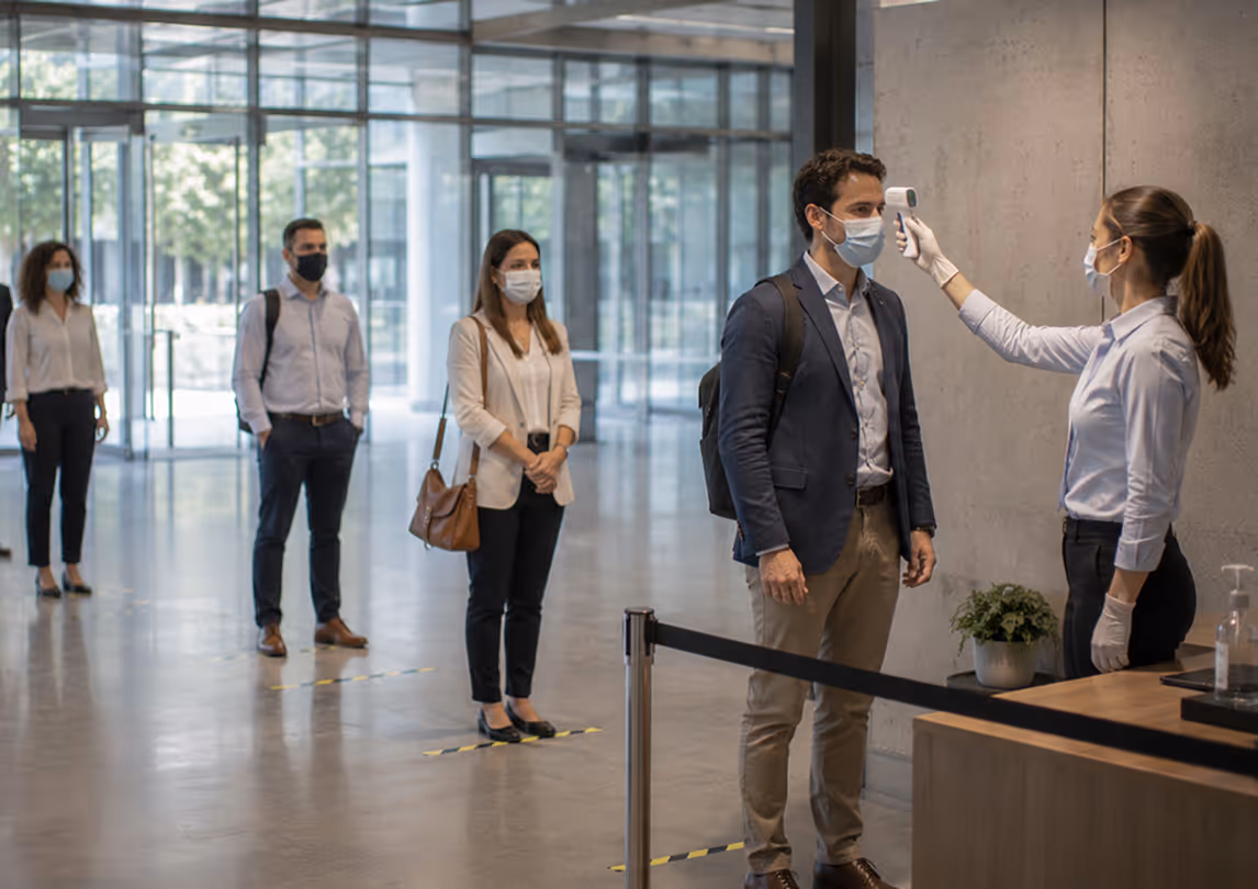 Employee temperature screening with masked workers showing the need for a simple workplace health check flow.