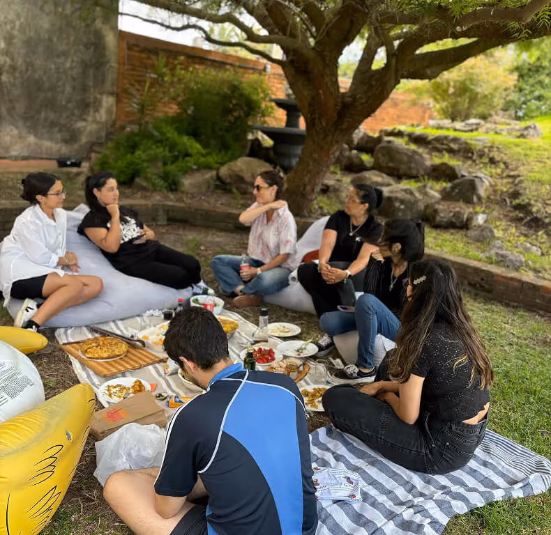 Team members sharing an outdoor picnic under a tree.