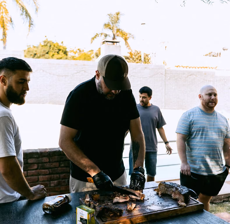 Team members grilling meat together at the weekly asado.