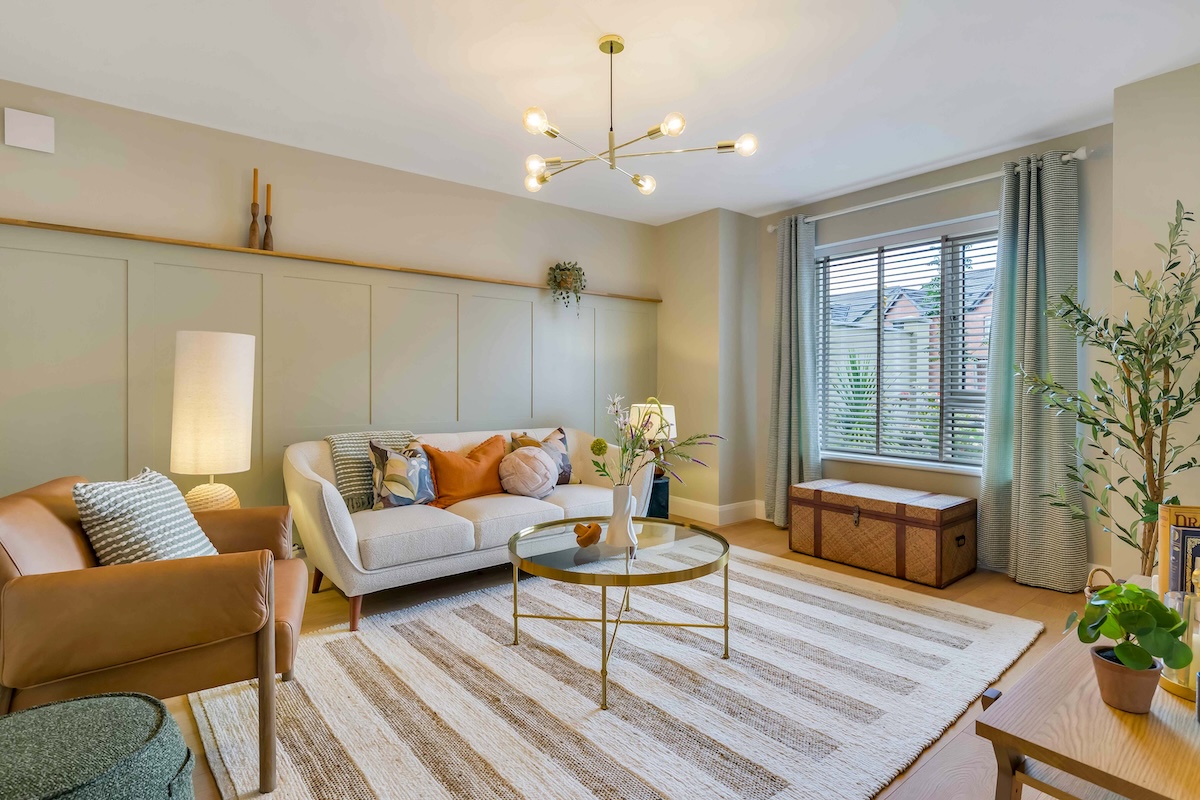 Modern living room with beige sofa, leather chair, round coffee table, and window with blinds and curtains.