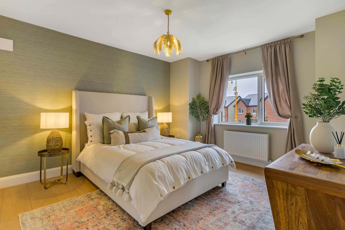 Well-lit bedroom with a white bed, bedside lamps, curtains, plants, and a wooden dresser.