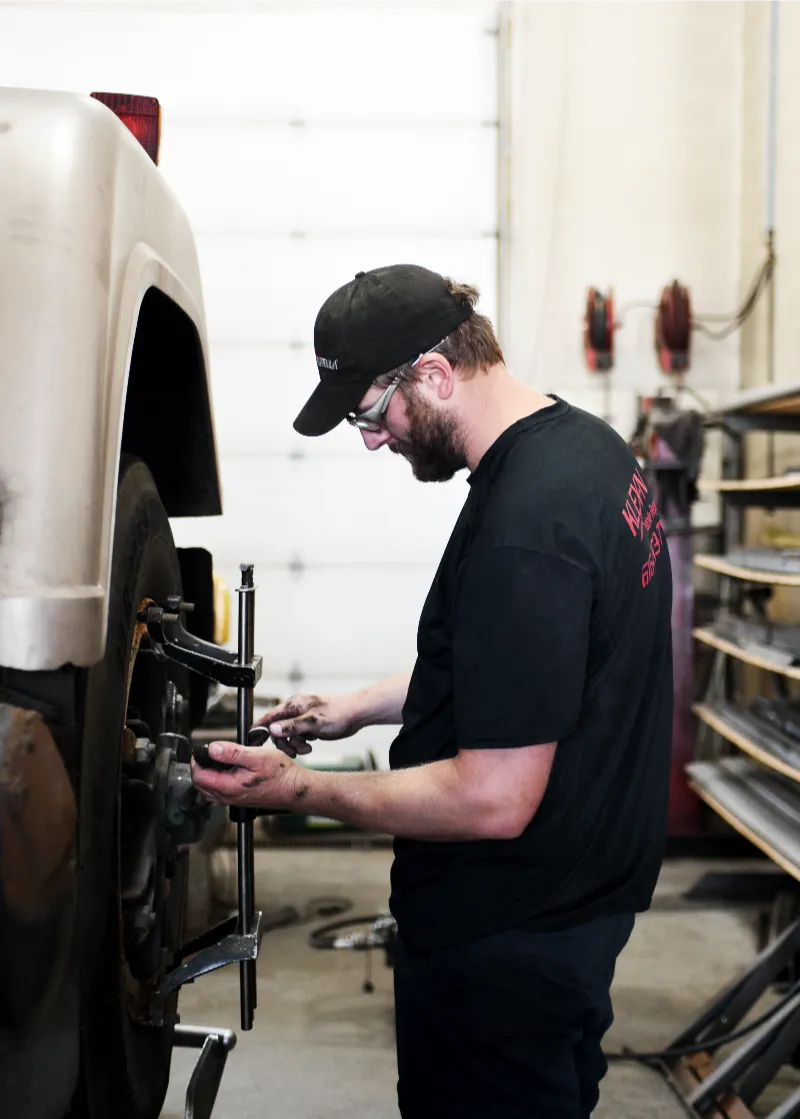 Wheel alignment on a heavy-duty pickup as a technician adjusts the tire hub in a repair bay.