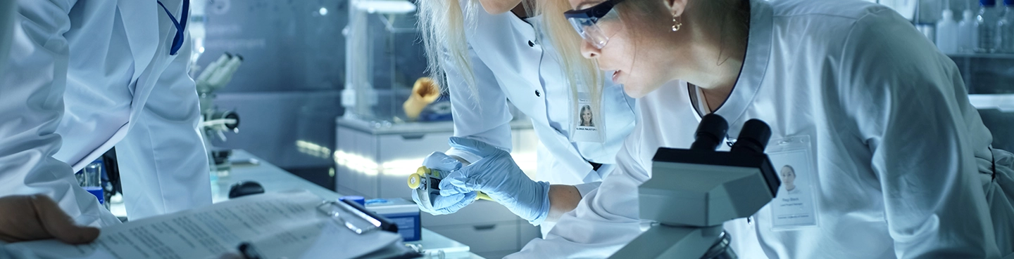 Scientists analyzing samples under a microscope in a laboratory environment.