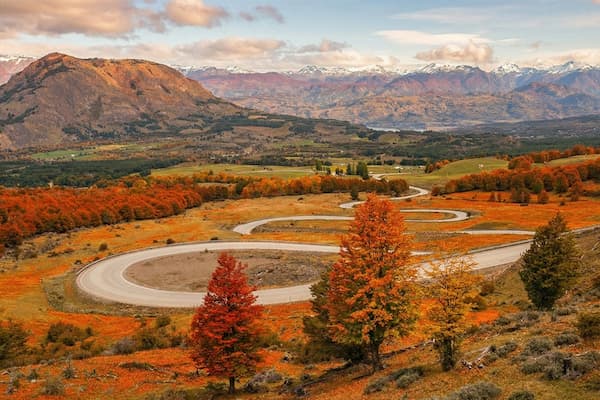 Breathtaking autumn view of Cerro Castillo in Patagonia, Chile, with snow-dusted peaks and vibrant orange forests. A scene that perfectly captures the serene and wild beauty of the Aysén Region, calling for your next adventure.