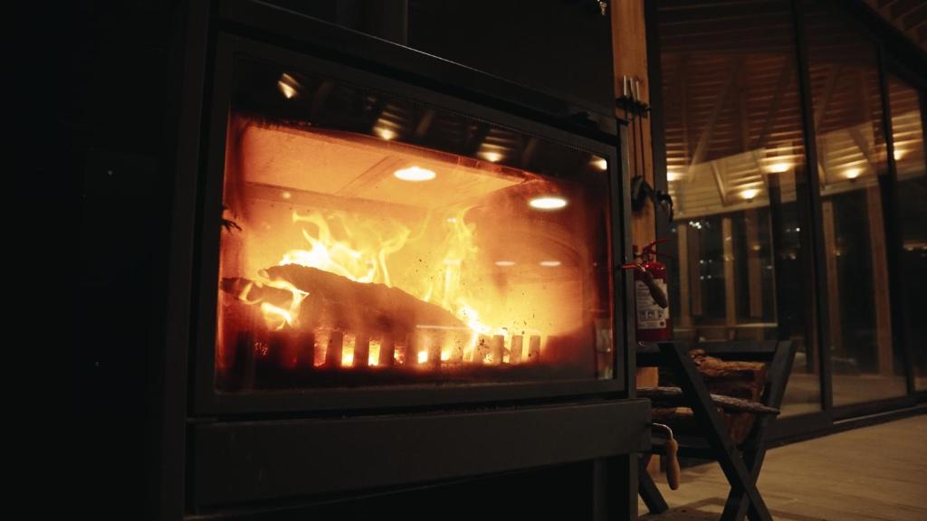 Wood-burning fireplace glowing inside Bahia Murta House on a Patagonian evening