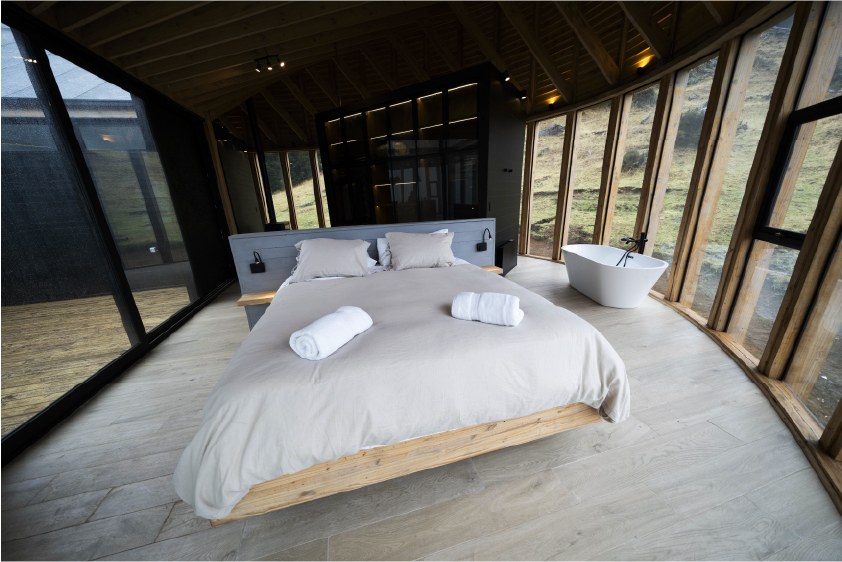 Spacious living area with glass walls opening to turquoise waters of Lago General Carrera