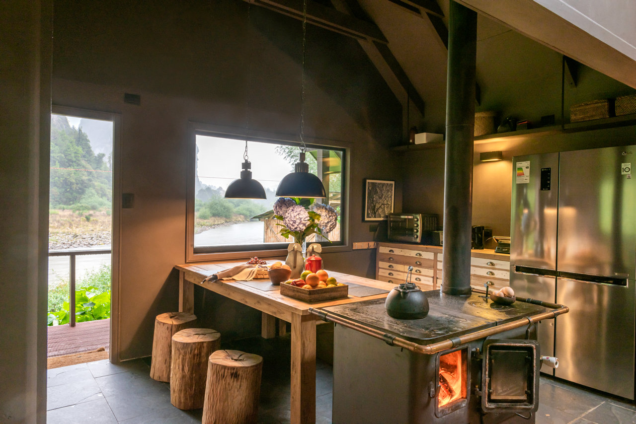 Kitchen and dining area with a wood stove in a Carretera Austral lodge