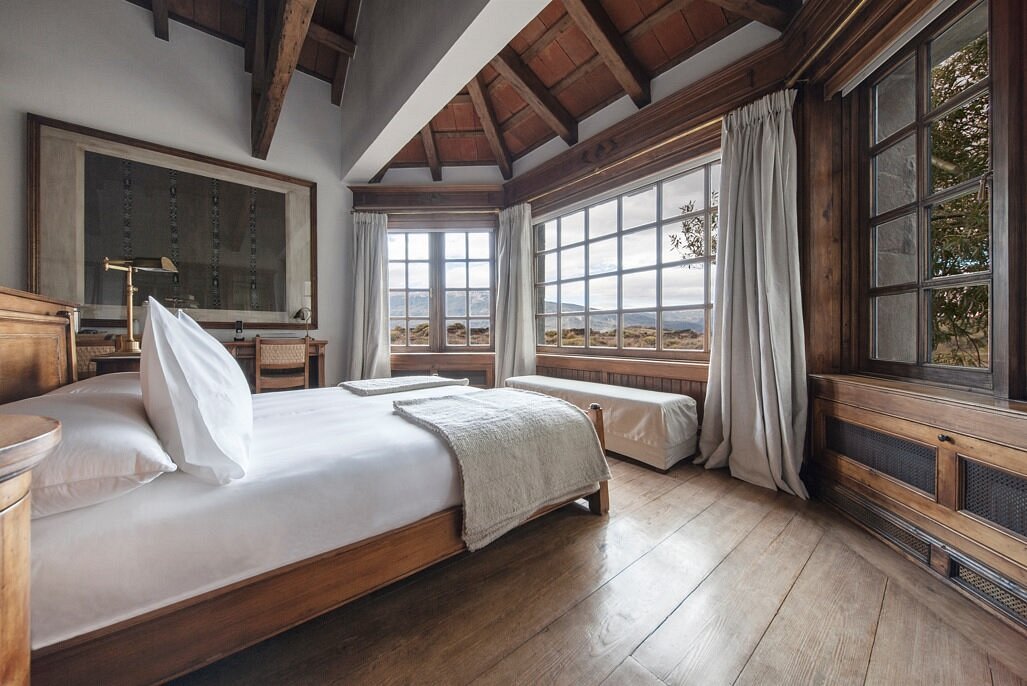 Corner bedroom with wooden beams and steppe views, Patagonia National Park lodge, Aysén