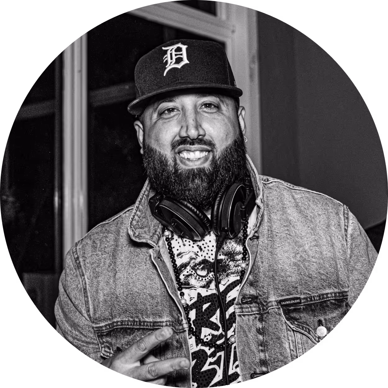 A smiling DJ with headphones around his neck.