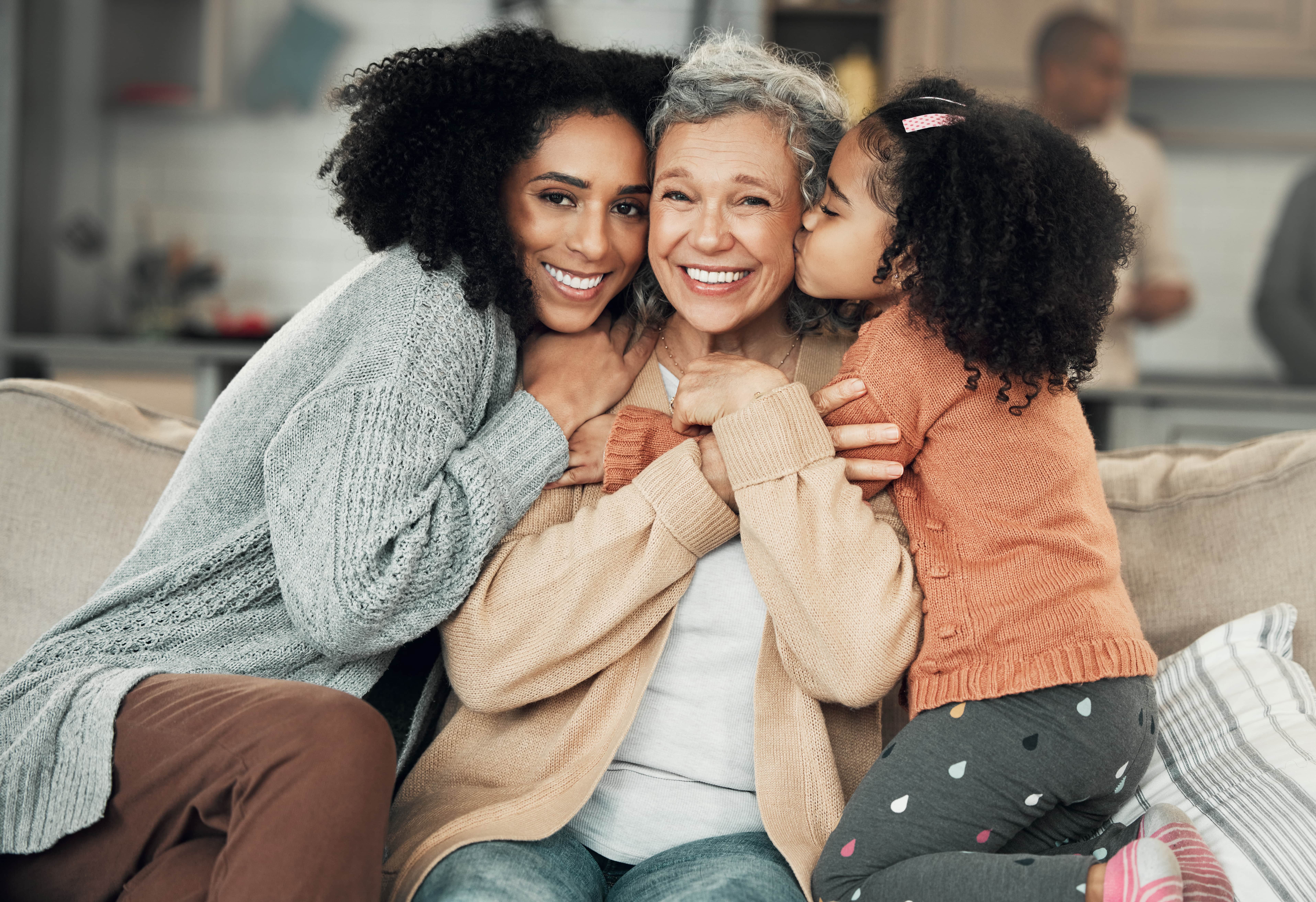 family on couch smiling and kissing cheek stock image