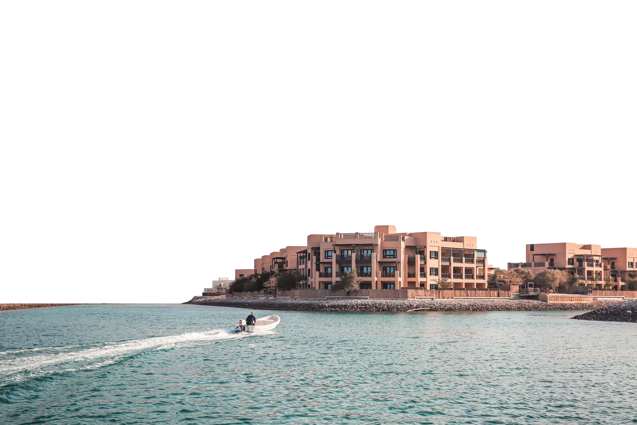 Part of a parallax effect. This foreground layer moves at a different speed to the background layer, creating a parallax effect. Atana Musandam property image taken from the water with the mountains in the background. A small speedboat rides in from the left of the image.