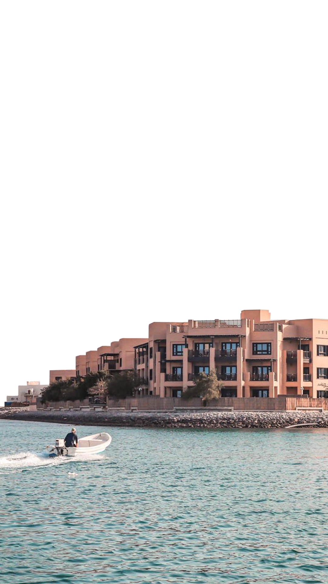Part of a parallax effect. This foreground layer moves at a different speed to the background layer, creating a parallax effect. Atana Musandam property image taken from the water with the mountains in the background. A small speedboat rides in from the left of the image.